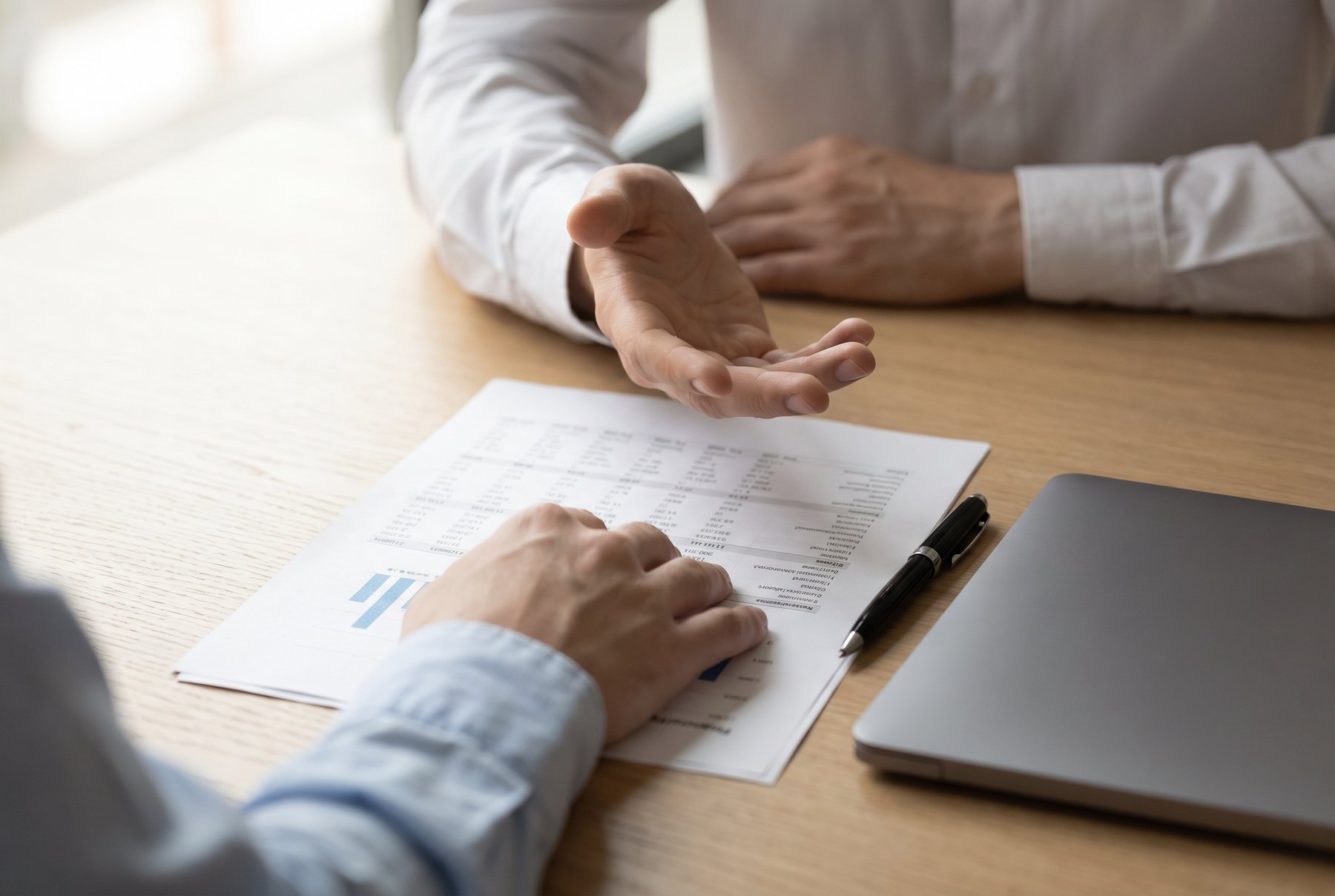 Two advisers going through a printed statement together at a table